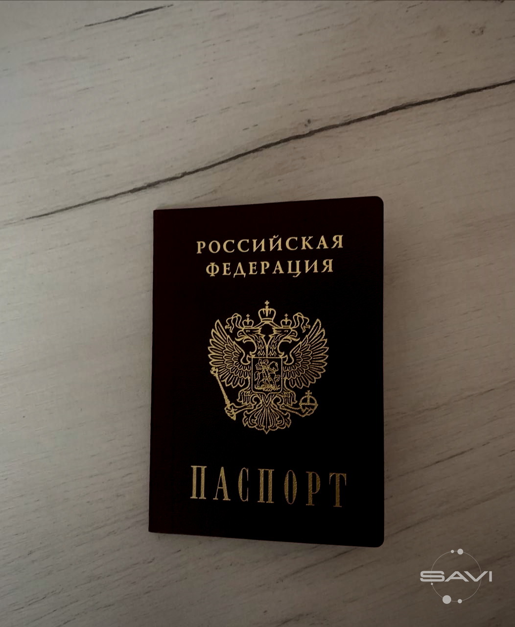 Закрытый бордовый паспорт РФ лежит на светлом деревянном столе